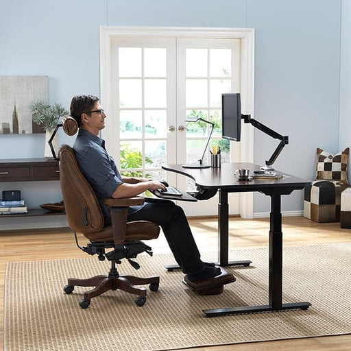 Man using the sitting feature of the AdaptDesk Standing Desk in his home office